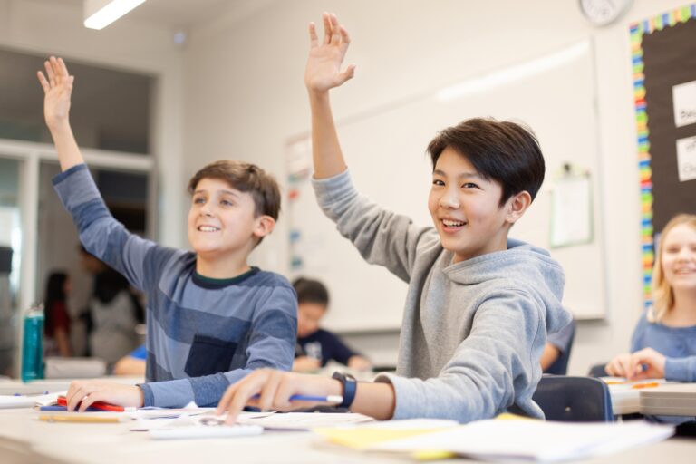 Two students raising their hands in class