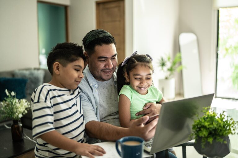 Father searching on laptop with his two kids