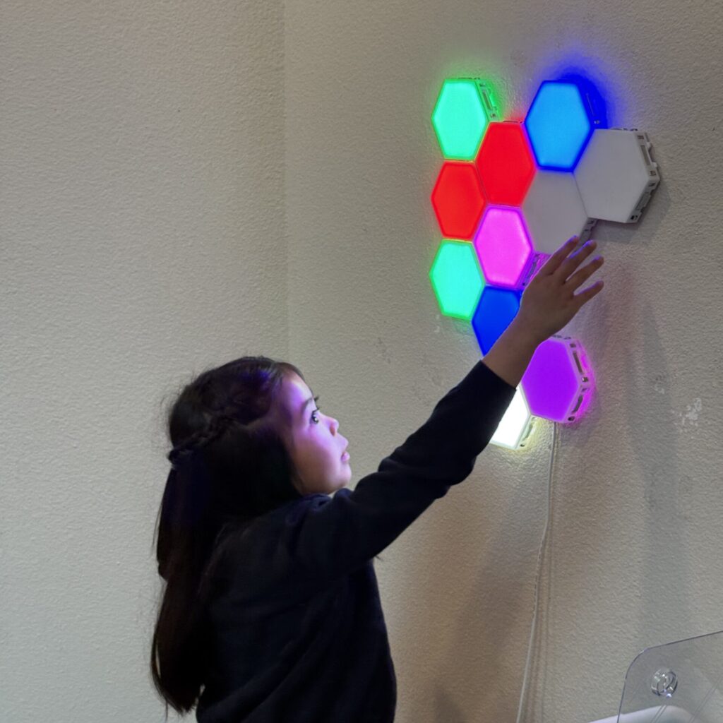 Child playing with light up tiles on the wall